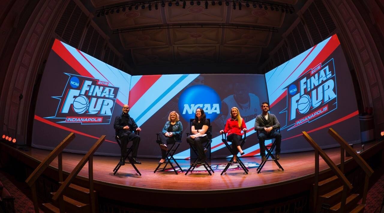 Five INNOVATIVE employees standing in for camera blocking on stage. Sitting in front of a large screen that says NCAA Final Four.