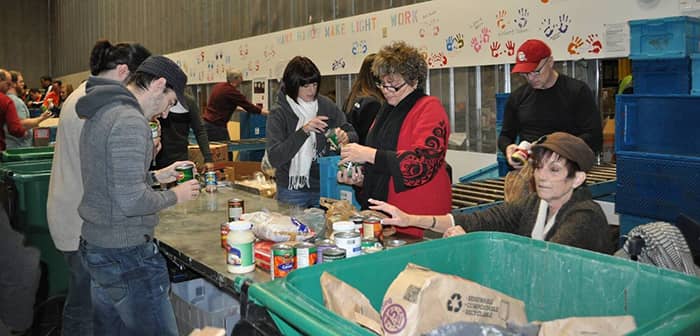 An image of several employees standing at a table sorting food goods for a company service day.